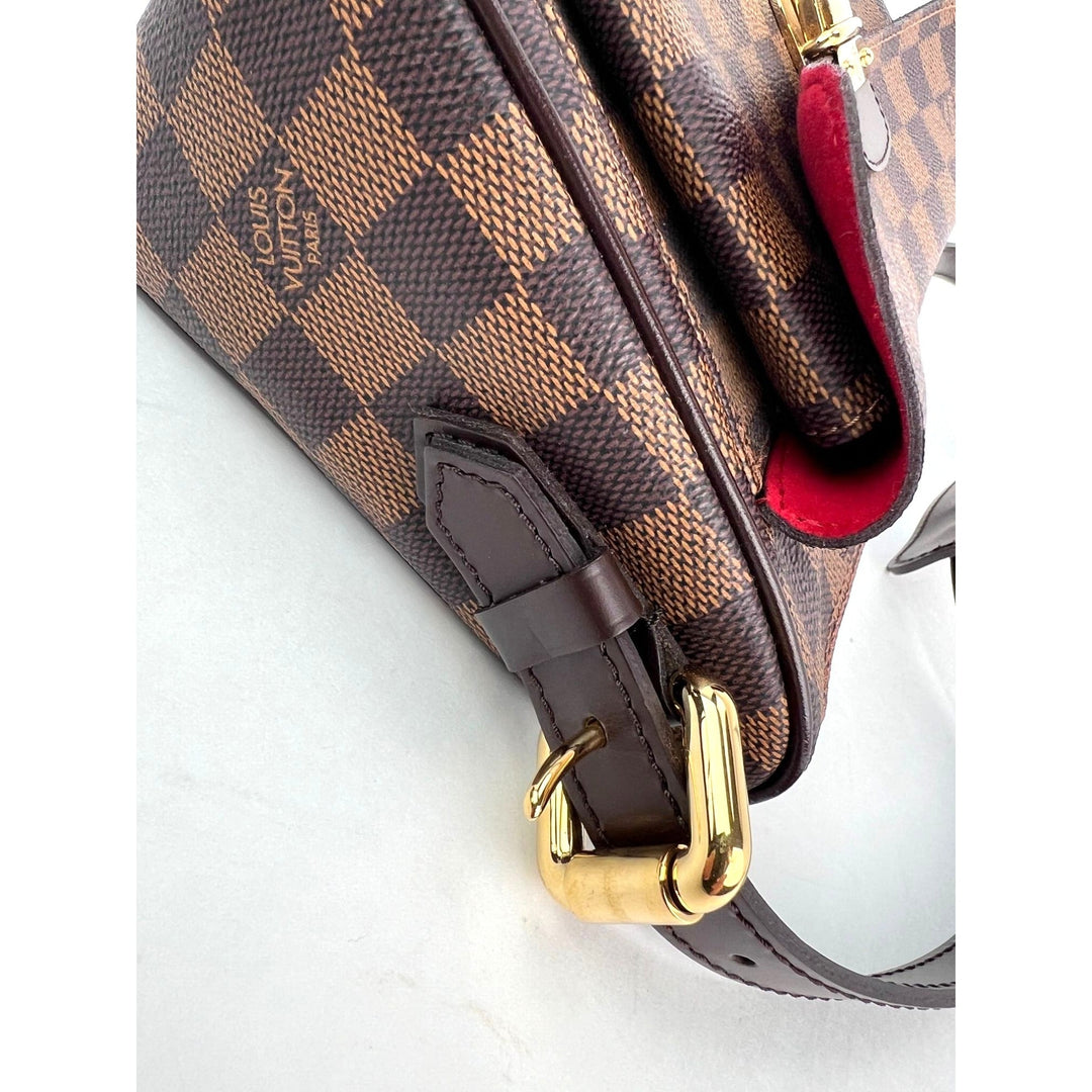 Louis Vuitton handbag with brown checkered pattern and gold hardware on a white background