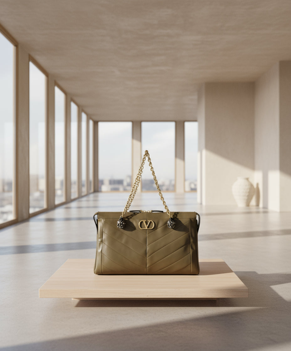 Brown handbag with gold chain and logo on a white background