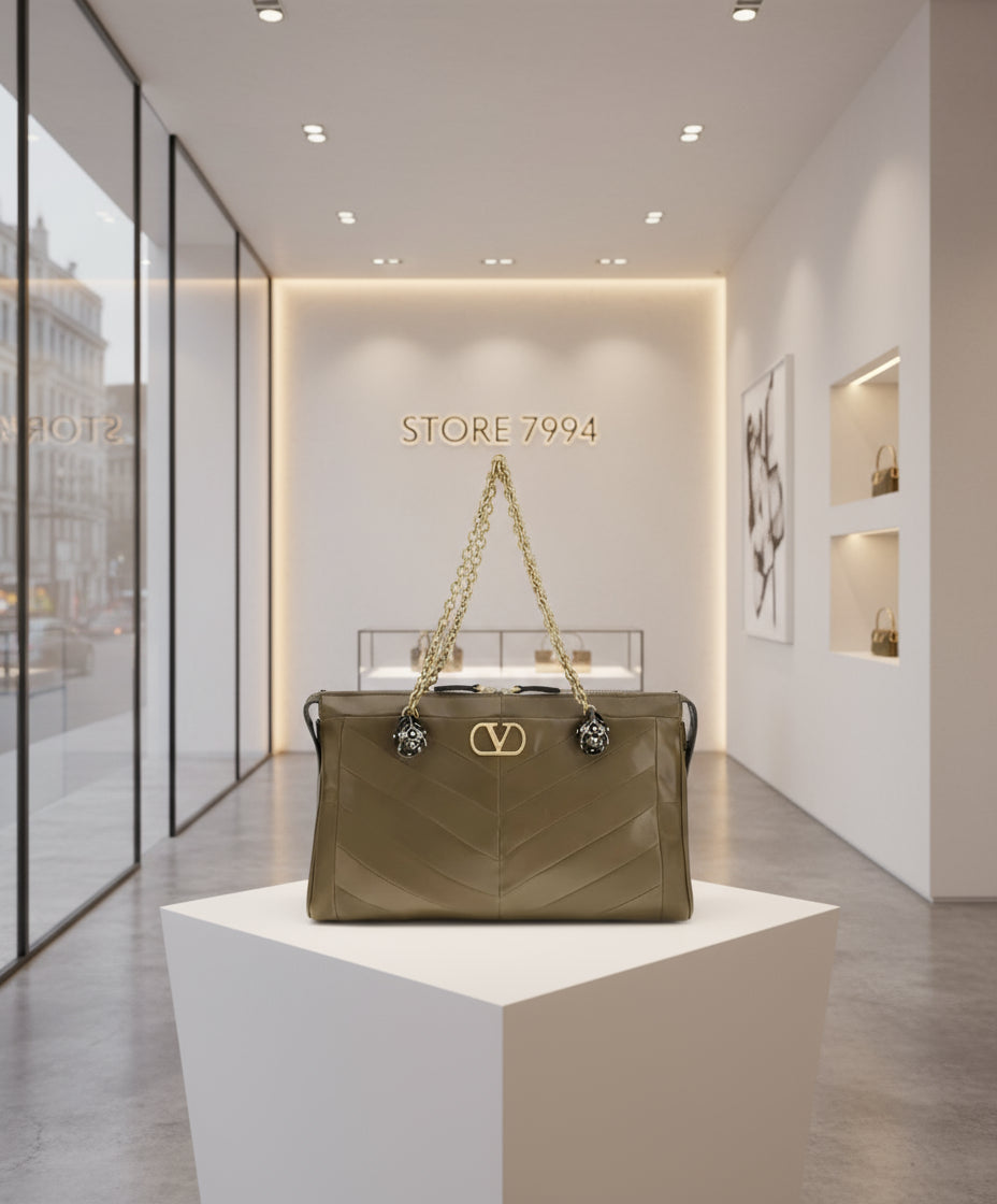 Brown handbag with gold chain and logo on a white background