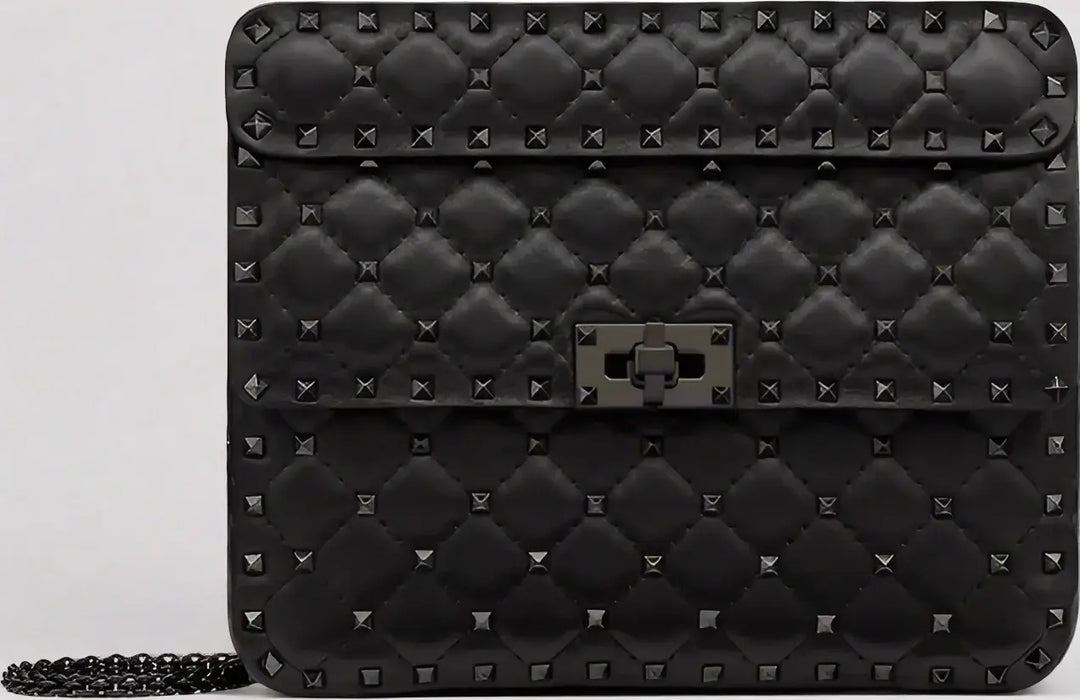 Black quilted handbag with stud details on a light gray background