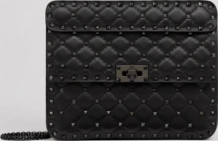 Black quilted handbag with stud details on a light gray background
