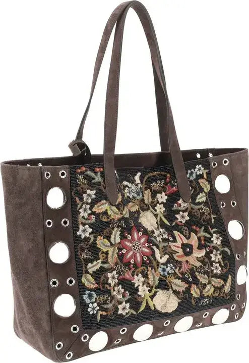 Brown handbag with floral embroidery and circular cutouts on a white background