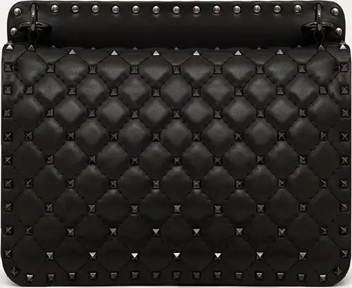 Black quilted handbag with studs on a black background