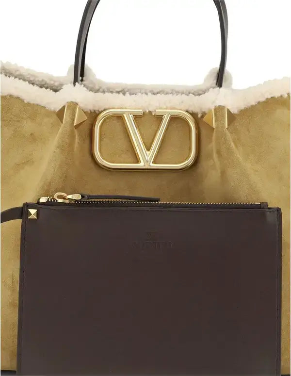 Tan handbag with gold logo and black pouch on a white background