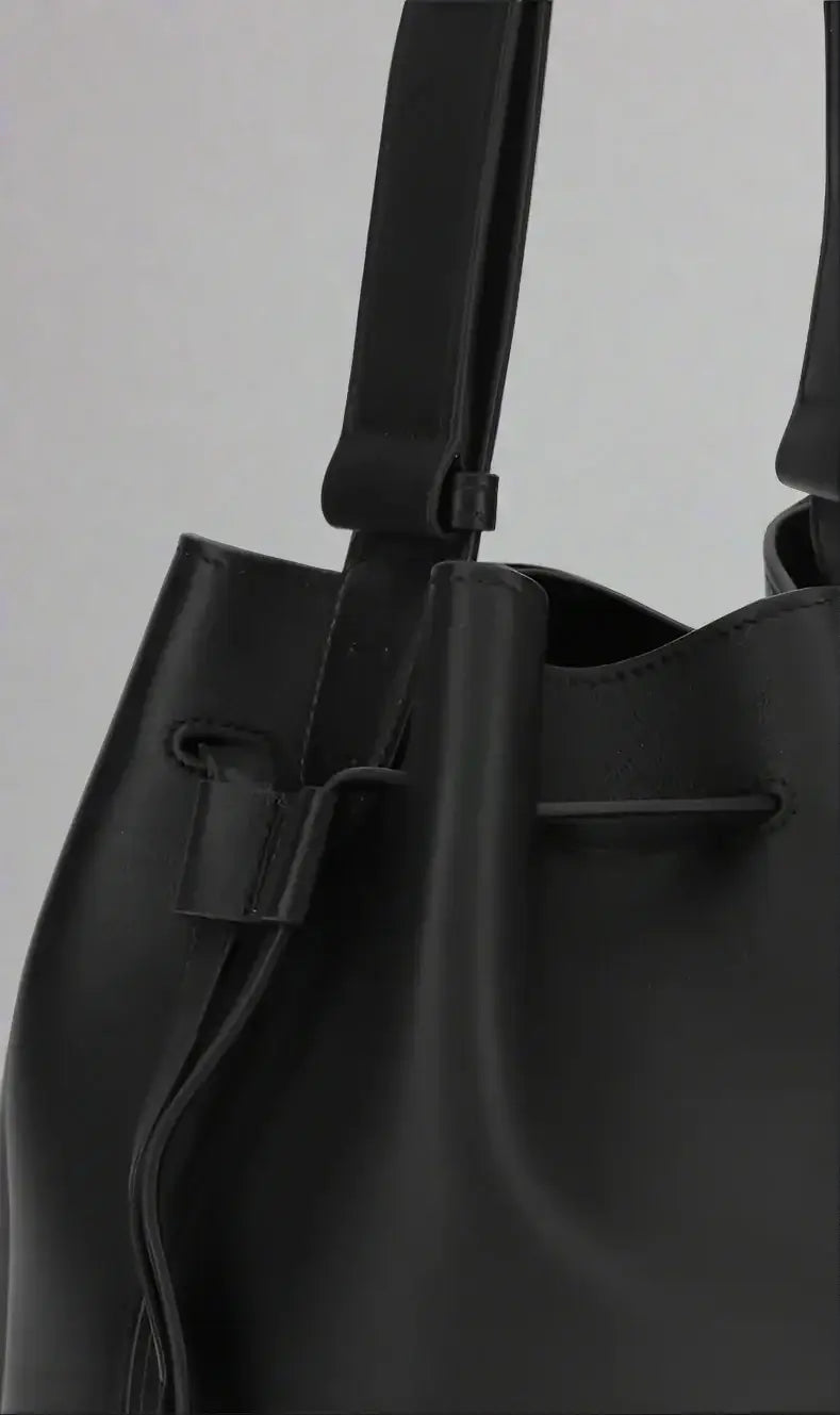 Black leather handbag with drawstring on a white background