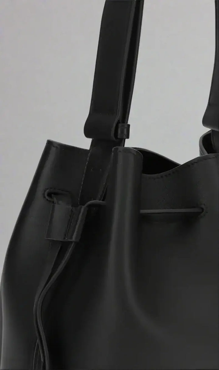 Black leather handbag with drawstring on a white background