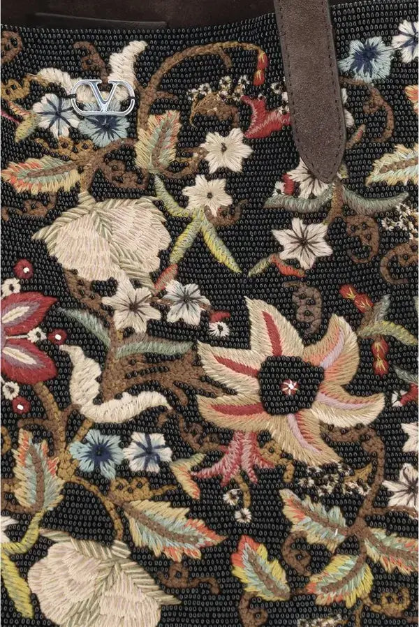 Close-up of a floral embroidered fabric with intricate patterns on a black background.