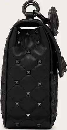 Black quilted leather backpack with studs on a beige background