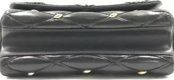 Black quilted handbag with gold hardware on a black background