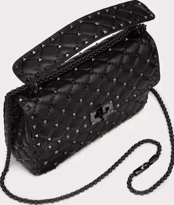 Black studded handbag with chain strap on a light gray background