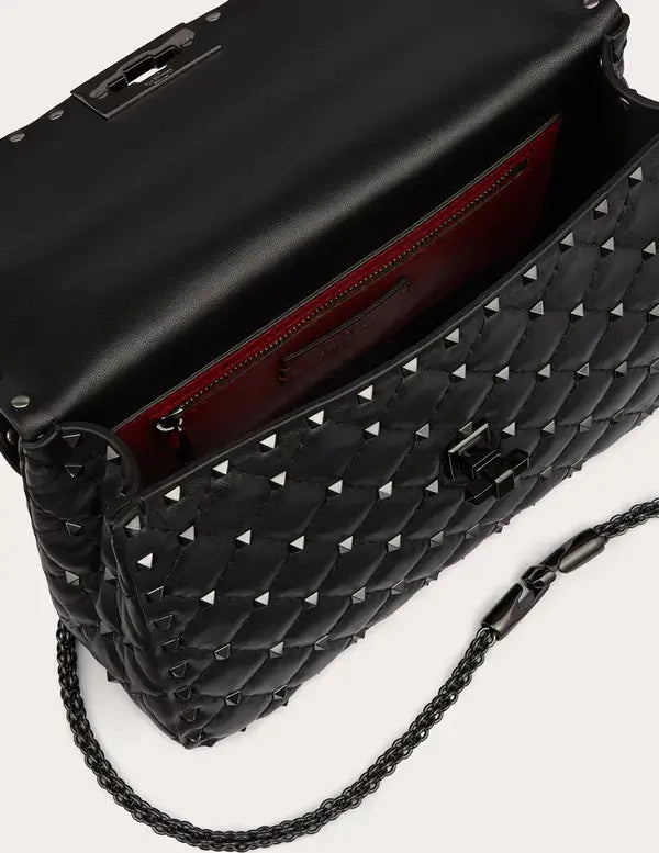 Black studded handbag with chain strap on a light gray background