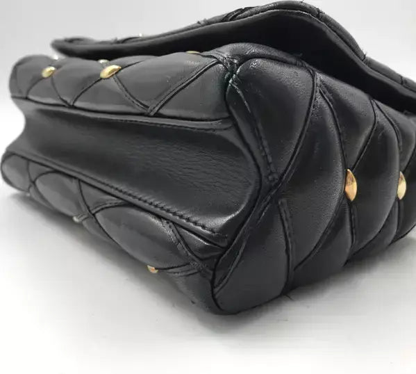 Black quilted handbag with gold studs on a white background