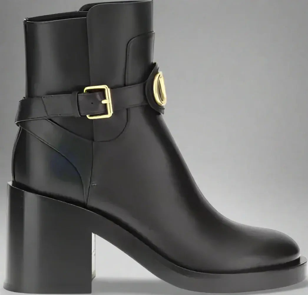 Black ankle boot with gold buckle on a white background
