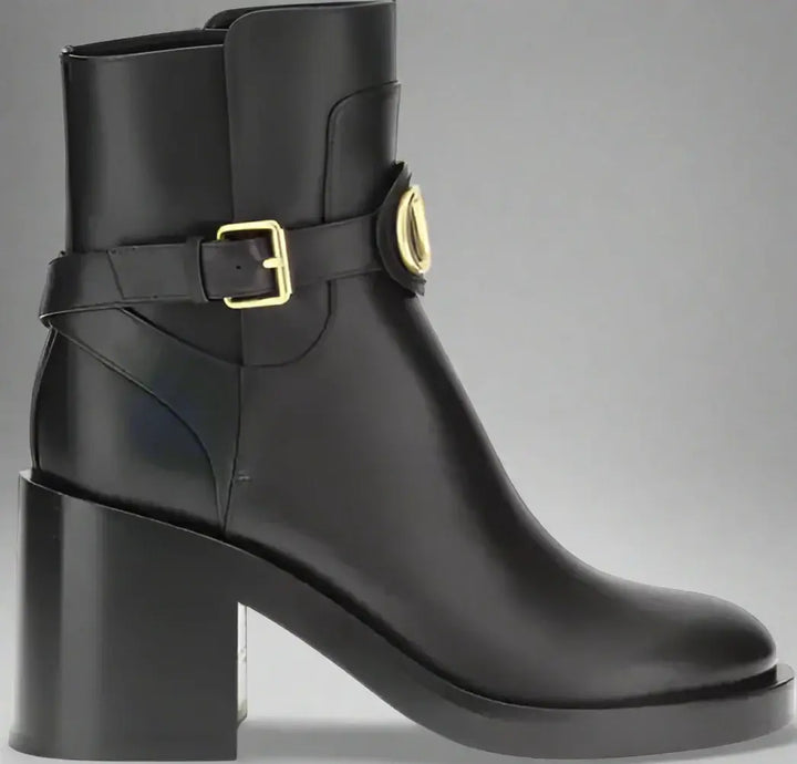 Black ankle boot with gold buckle on a white background