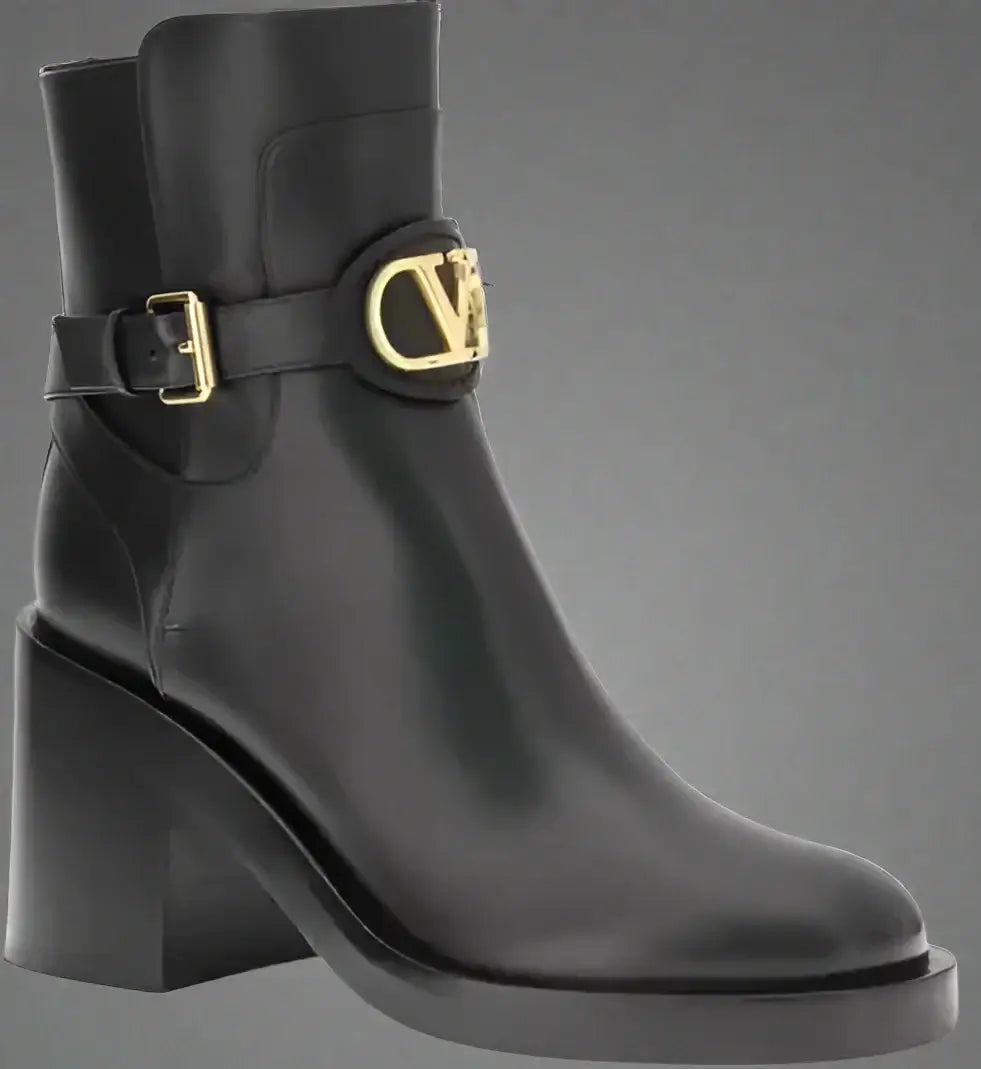 Black ankle boot with gold buckle on a white background