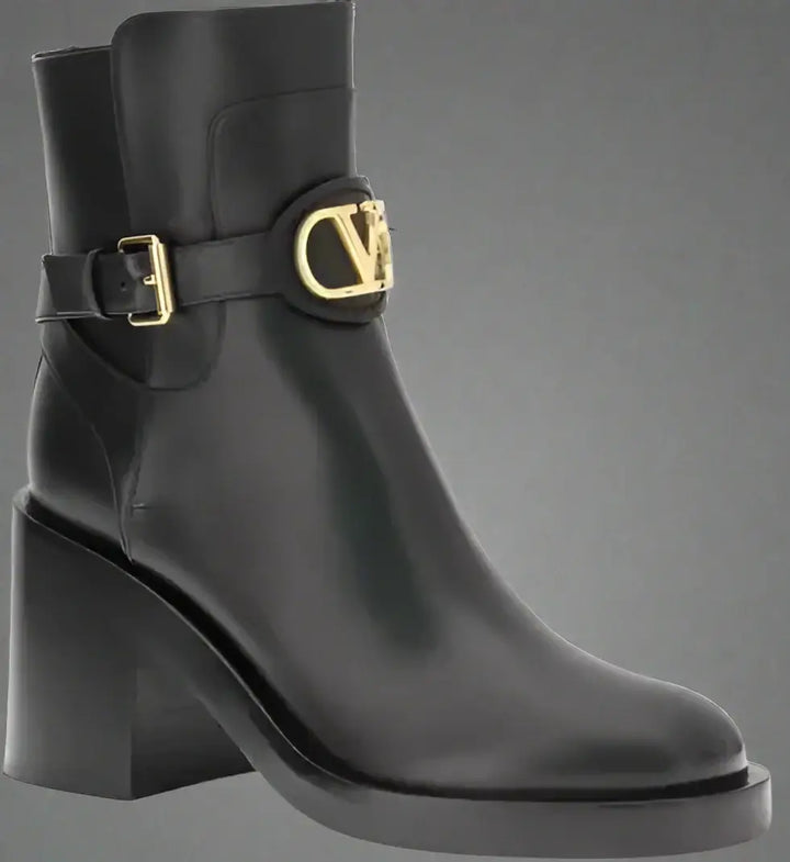 Black ankle boot with gold buckle on a white background