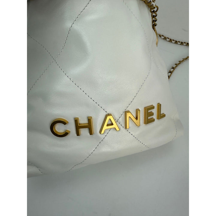 White quilted handbag with gold 'Chanel' logo on a light gray background