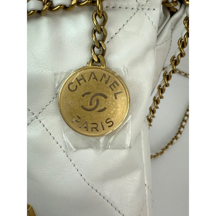 Gold Chanel logo tag on a white quilted handbag