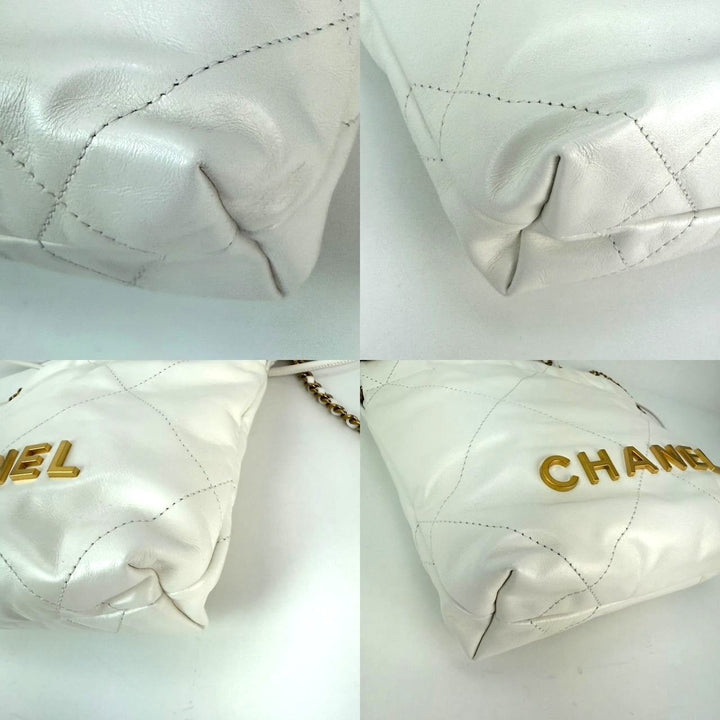 Close-up of a quilted white handbag with gold 'Chanel' branding on a light gray background.