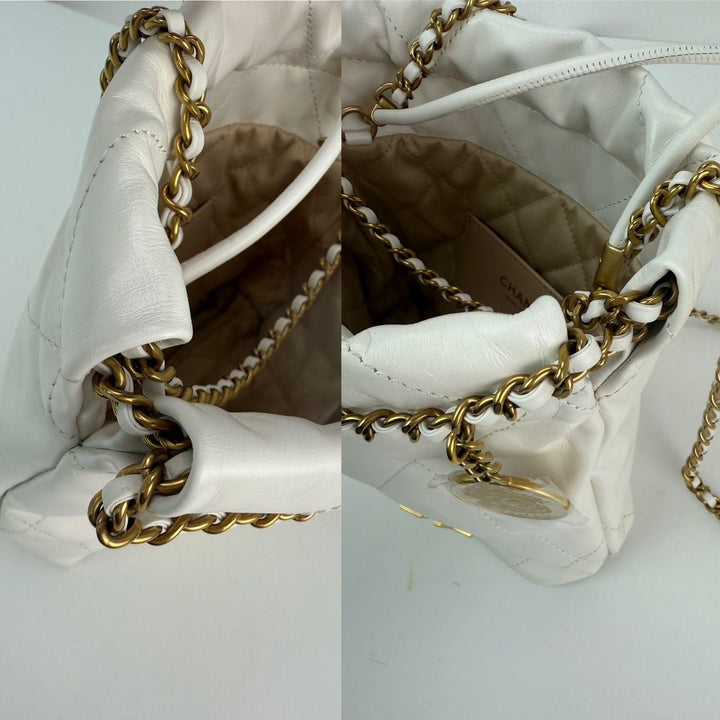 Close-up of a white handbag with gold chain detail on a light gray background