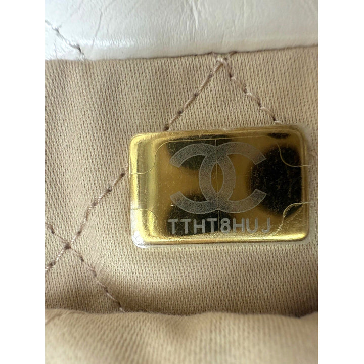 Gold Chanel logo on a beige textured surface