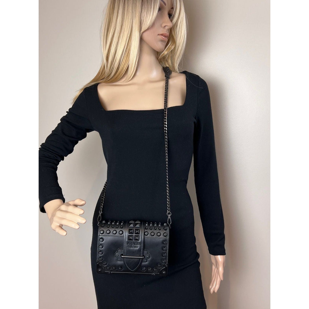 Mannequin wearing a black dress with a studded black handbag.